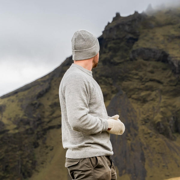 Mies katsoo vuoristoon päin päällään alpakan villasta valmistetut Ursus-pipo, Pilvi-tumput ja Hurma-villapaita