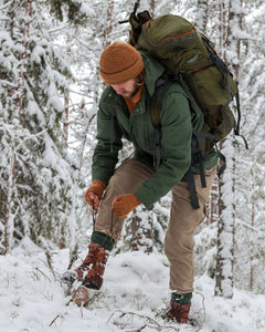 Mies sitoo kenkää talvisessa metsässä